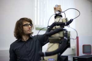 Florian Müller, Projektmitarbeiter der Fakultät Elektrotechnik und Informationstechnik der HTWK Leipzig, dirigiert den handgeführten Roboter, der auf der Fachmesse INTEC zu sehen sein wird. Quelle: Kristina Denhof 