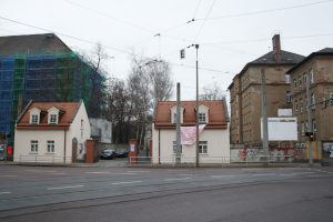 Die zwei Schulgebäude in der Gorkistraße, die zum Gymnasium werden sollen - und ein Protesttransparent gegen die eingesparte Brücke am Eingang zum Friedhof. Foto: Ralf Julke