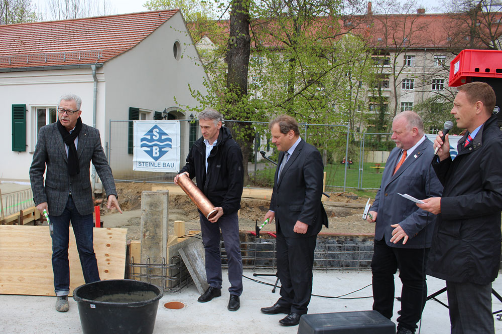 Unter dem Grundstein, der sich auf der fertig betonierten Bodenplatte befindet, wurde zuvor eine Schatulle versenkt, in der sich Baupläne, der Programmablauf der Grundsteinlegung sowie das Jahresheft des Berufsbildungswerkes befinden. Hilmar Hörschelmann von Steinle Bau (links), Bürgermeister Prof. Dr. Thomas Fabian (Mitte) und Jörg Linsel, Michael Preuß (kaufmännischer Geschäftsführer) und Tobias Schmidt (Hauptgeschäftsführer) vom Berufsbildungswerk Leipzig. Foto: M.H. / BBW