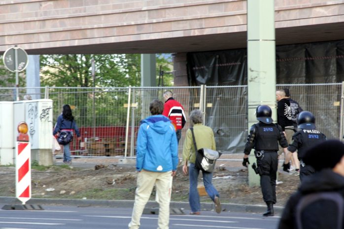 Ein junger Legida-Demonstrant hat die Farben einer Kriegsflagge an und ein Kreuz auf der Brust