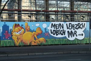 Am Bauzaun an der Alten Hauptpost hat sich der Graffitiverein was einfallen lassen. Foto: Ralf Julke