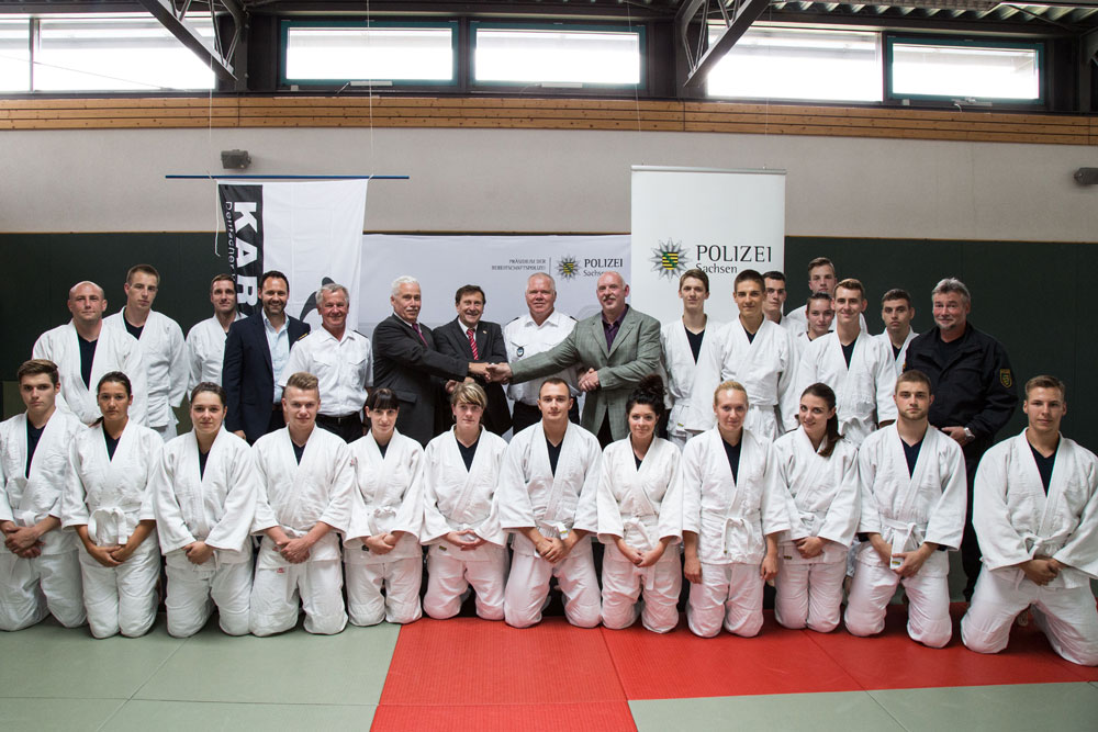 von links: Christian Dahms, Generalsekretär des LSB Sachsen; Dieter Hanitsch, Inspekteur der Polizei Sachsen; Dr. Michael Wilhelm, Staatssekretär des SMI; Wolfgang Weigert, Präsident des Deutschen Karate Verband e.V.; Horst Kretschmar, Leiter des Präsidiums der Bereitschaftspolizei; Thomas Hagemann, Vizepräsident des Sächsischen Karatebund e.V.; umrahmt von Auszubildenden der Polizeifachschule Leipzig. Foto: Daniel Adner