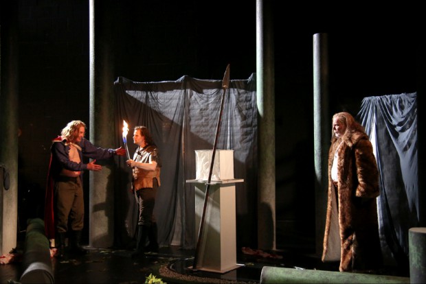 Die Waffe ist wieder da und die Welt der Gralsritter ist wieder in Ordnung. Raimund Nolte (Amfortas), Benjamin Bruns (Parsifal), Jukka Rasilainen (Gurnemanz). Ein Stein verkörpert den Gral. Foto: Bayreuther Festspiele / Jörg Schulze