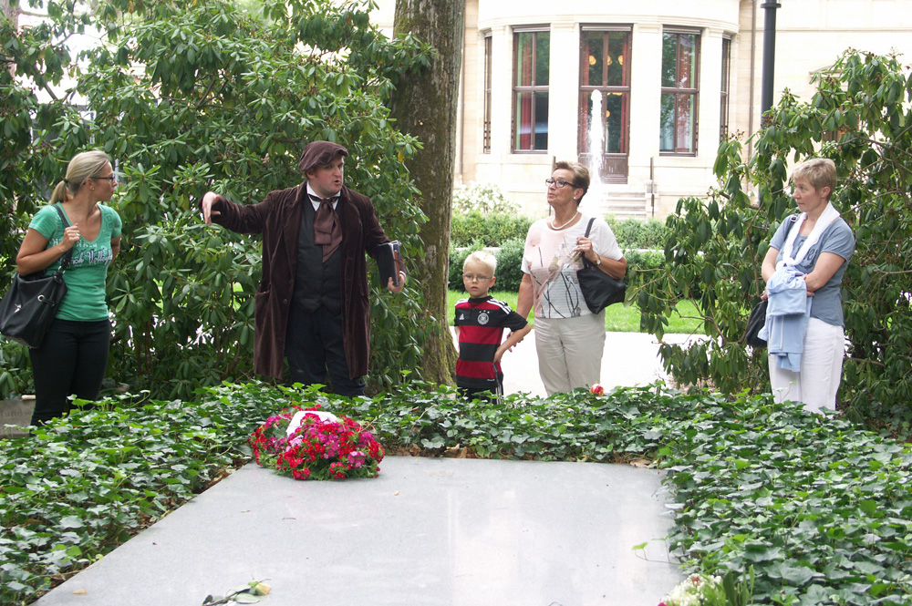 Richard Wagner leibhaftig an seinem Grab! Ein Bayreuther Living-History-Darsteller und Touristen machen eine Kutschfahrtpause an der Familiengruft im Garten der „Villa Wahnfried“. Foto: Karsten Pietsch