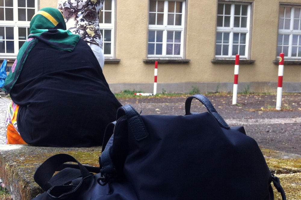 Eine Frau hat erschöpft vor der Ernst-Grube Halle Platz genommen. HIer "wohnen" derzeit rund 400 Flüchtlinge noch bis März 2016 in Leipzig. Foto: L-IZ.de