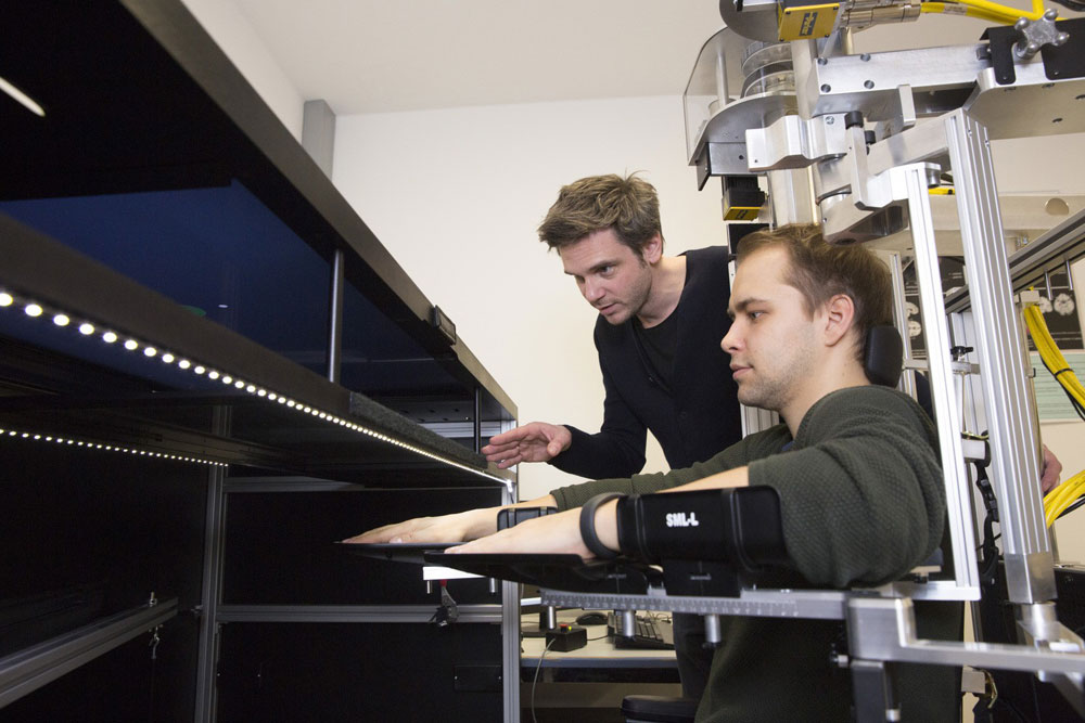 Dr. Bernhard Sehm von der Tagesklinik für Kognitive Neurologie erklärt die Funktionsweise des Exoskeleton-Roboters. Foto: Stefan Straube / UKL