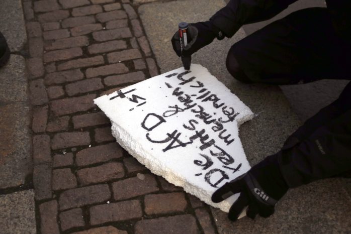 Demonstrant widmet zerstörtes Schild um. Foto: Alexander Böhm
