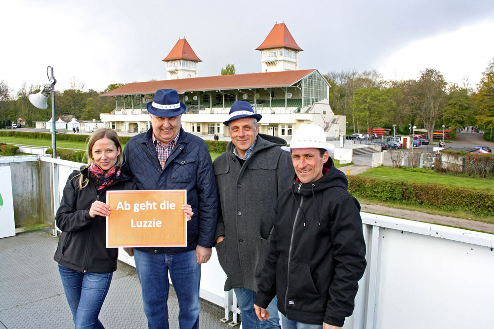 Scheibenholz-Mitarbeiterin Franziska Margalle, Jürgen Funke (Präsident LRRS e.V.), Alexander Leip (Geschäftsführer Scheibenholz GmbH) und Pferdetrainer Marco Angermann (v.l.) freuen sich auf Sonntag und tragen den neuen Hut der Galopprennbahn zur Probe. Foto: Corinna Schulze/Scheibenholz GmbH