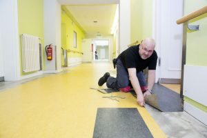 Mike Wanzke, Fachmann der Firma Wohnfühl Konzepte GmbH, verlegt den neuen Fußboden in den Gängen des UKL-Zentrums für Psychische Gesundheit. Foto: Stefan Straube/UKL