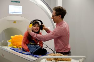 Mithilfe der Attrappe eines Hirnscanners bereitet sich eine junge Probandin auf ein Experiment vor. Foto: MPI CBS
