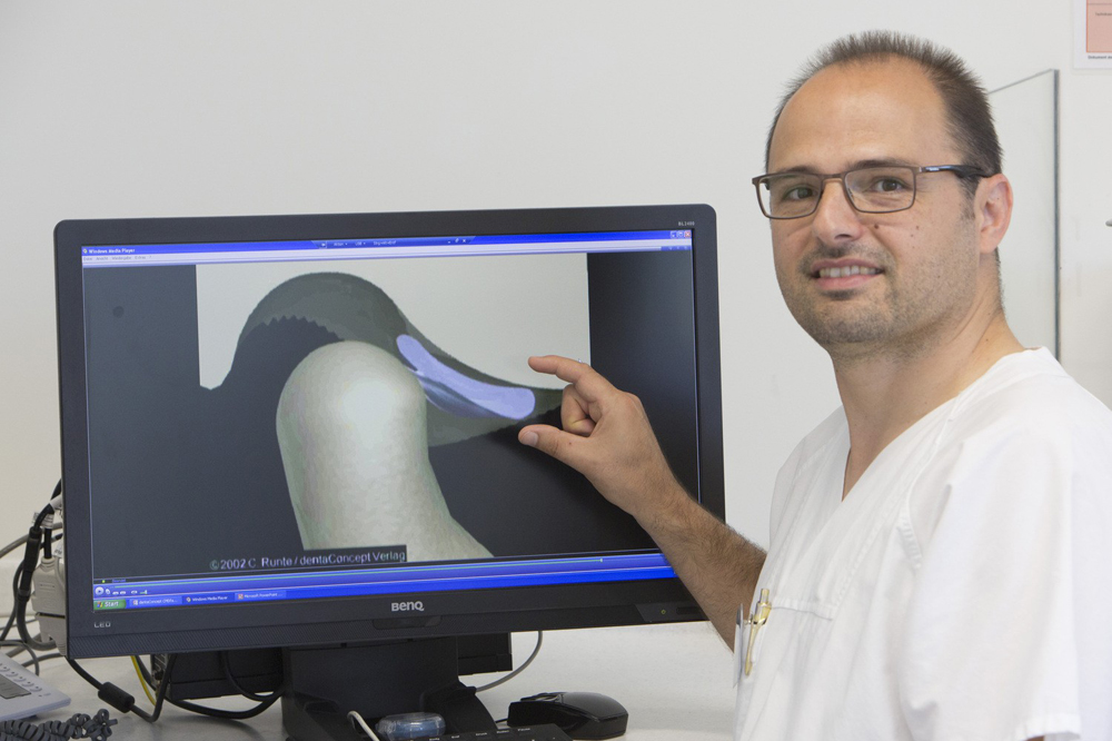 Dr. Oliver Schierz, Leiter des Bereichs Klinische Prothetik an der Poliklinik für Zahnärztliche Prothetik und Werkstoffkunde des Universitätsklinikums Leipzig, zeigt am Bildschirm eine grafische Darstellung einer verschobenen Knorpelscheibe zwischen Gelenkköpfchen und Gelenkgrube. Foto: Stefan Straube/UKL
