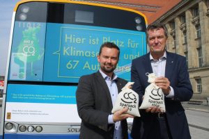 Marc Backhaus und Ronald Juhrs vor dem Bus mit der Klimaschutz-Werbung. Foto: Ralf Julke