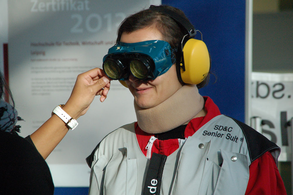 Gar nicht so einfach, den Alterssimulationsanzug ohne Hilfe überhaupt anzulegen – geschweige denn, sich damit zu bewegen. (Impression vom „Tag der Familie“ an der HTWK Leipzig 2015 mit dem Schwerpunkt „Pflege“). Foto: Reinhard Franke/HTWK Leipzig