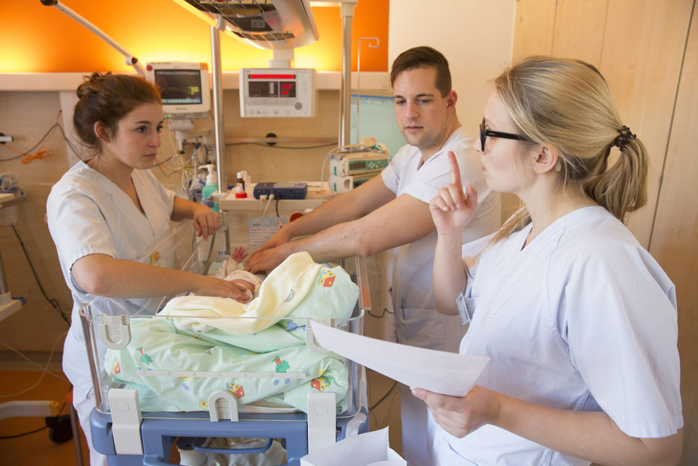 Die beiden Azubis Lisa Köberling (links) und Vivien Plickert kümmern sich gemeinsam mit Pfleger Erik Emrich um einen kleinen Patienten auf der Station E 1.2. Foto: Stefan Straube