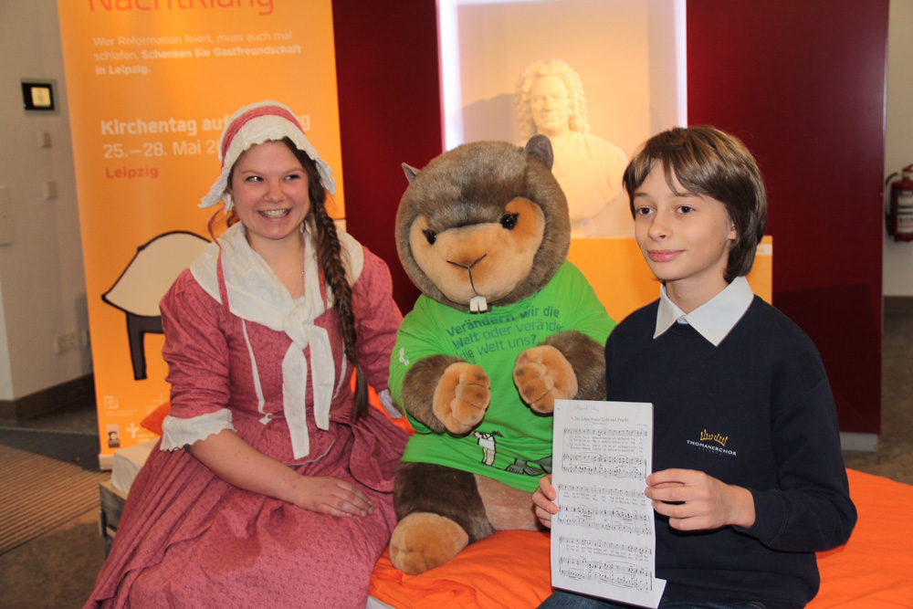 Anna Magdalena Bach (dargestellt von Oke Löffler, Praktikantin im Bach-Archiv) und Thomaner Nathanael Vorwergk mit Maskottchen Murmeltier Manni. Foto: „Bach-Archiv Leipzig/Franziska von Sohl