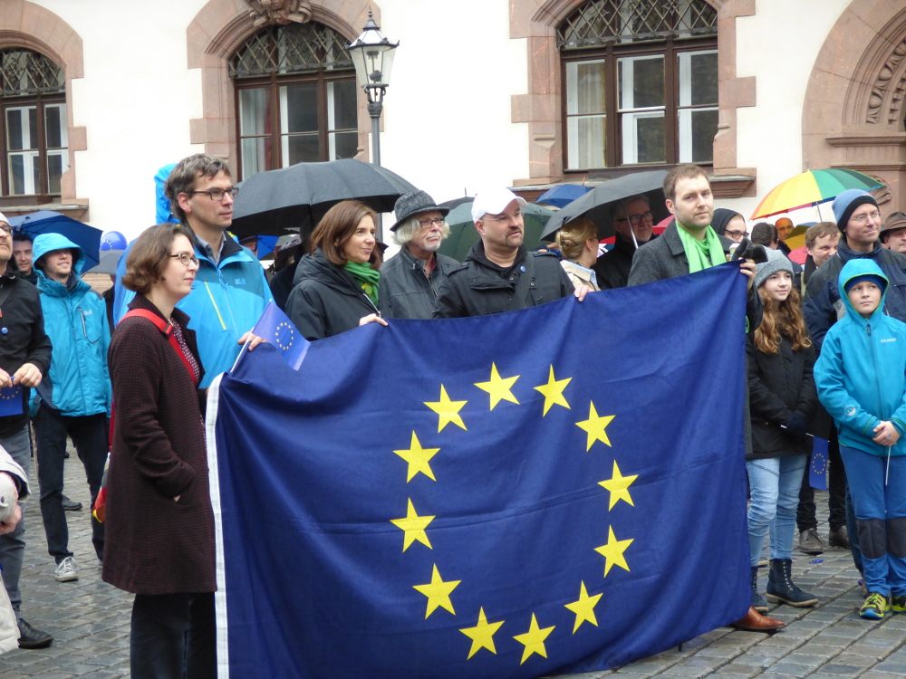 Versammlungsteilnehmer an der EU-Flagge, 3. v.l.: Die grüne Politikerin Katrin Göring-Eckardt. Foto: Lucas Böhme
