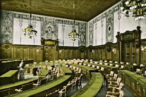 Der Stadtverordnetensaal im Neuen Rathaus in der Zeit um 1927 mit seiner Kassettendecke und den hölzernen Paneelen. Die Wandmalerei mit antikisierenden Prozessionsmotiven schuf der Kunstmaler Julius Mössel. Bis 2020 soll der Ratssaal umgebaut werden. Foto: Pro Leipzig Verlag