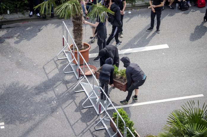Demonstrierende errichten eine Barrikade an den Landungsbrücken am Nachmittag des 07.07. mithilfe von Palmen und Blumentöpfen der anliegenden Restaurants sowie Absperrgittern der Polizei. Foto: Tim Wagner