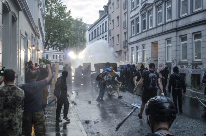 Demonstrierende setzten sich mit Schildern und Brettern gegen den Wasserwerfer zur Wehr bzw. greifen diesen an im Schanzenviertel. Foto: Tim Wagner