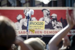 Klobürsten als Symbol gegen den Ausnahmezustand in Hamburg mit einem Schild #NoG20 vor der Bühne der "Welcome to Hell" Demo. Foto: Tim Wagner