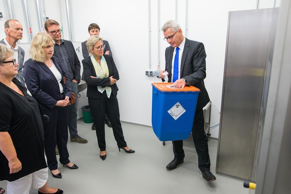 Sven Krage von der Herstellerfirma MMM (Münchner Medizin Mechanik mbH) (rechts) erklärt Klinikum-Geschäftsführerin Dr. Iris Minde (2.v.l.) und Staatsministerin Barbara Klepsch (vorne, 3.v.r.) den neuen Durchreiche-Autoklaven. Foto: Klinikum St. Georg