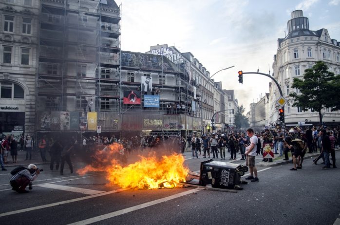 Mann pinkelt auf eine brennende Barrikade am Eingang zum Schulterblatt, vom neuen Pferdemarkt kommend. Foto: Tim Wagner