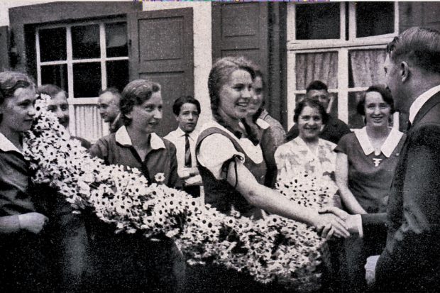Deutschland erwacht, aus der Reihe „Werden, Kampf und Sieg der NSDAP“ des „Cigaretten-Bilderdienst“ in Hamburg-Bahrenfeld: Hitlermädels begrüßen den Führer anlässlich der Wahlreise im Odenwald. © gemeinfrei