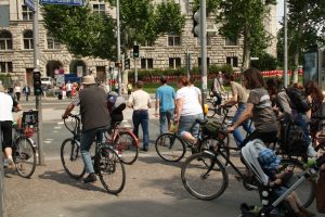 Gruppe von Radlern an Ampel, in Anfahrt über Straße begriffen.