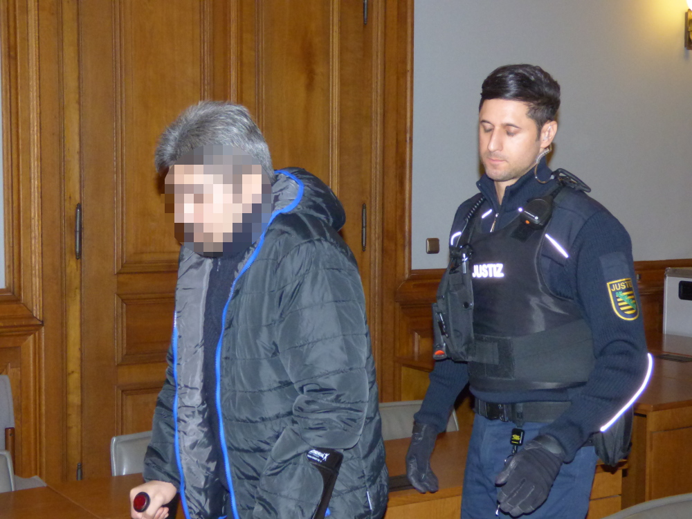 Ein Justizbeamter führt den Angeklagten Ghulam R. (39), der nach seinem Suizidversuch an Krücken geht, zur Anklagebank. Foto: Lucas Böhme