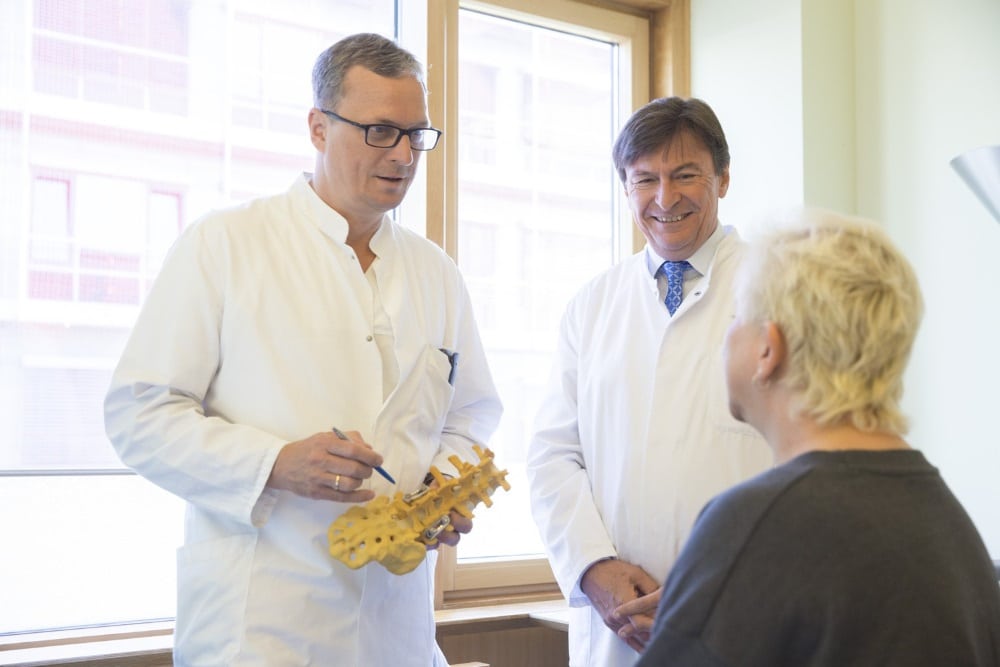 Im nun zertifizierten Wirbelsäulenzentrum am UKL arbeiten Orthopäden, Unfallchirurgen sowie Neurochirurgen eng zusammen. Prof. Christoph-E. Heyde (links), Leiter des Bereichs Wirbelsäulenchirurgie, und Prof. Jürgen Meixensberger (rechts), Direktor der Klinik und Poliklinik für Neurochirurgie, nutzen im Gespräch mit einer Patientin ein Modell eines Teils der Wirbelsäule zur Verdeutlichung. Foto: Stefan Straube/UKL