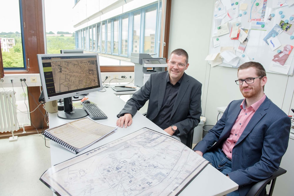 Prof. Dr. Stephan Laux (links) und Matthias Schneider mit den Armenlisten von 1832 und dem um 1845 entstandenen Stadtplan. Foto: Uni Trier