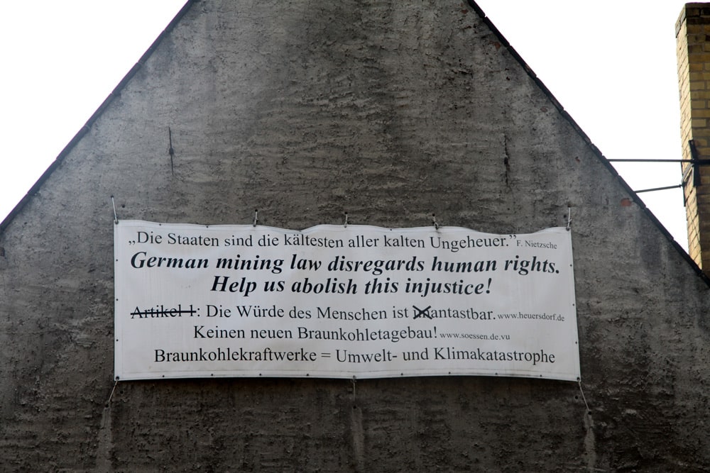 Plakat an rußgeschwärzter Wand in Pödelwitz. Foto: Matthias Weidemann