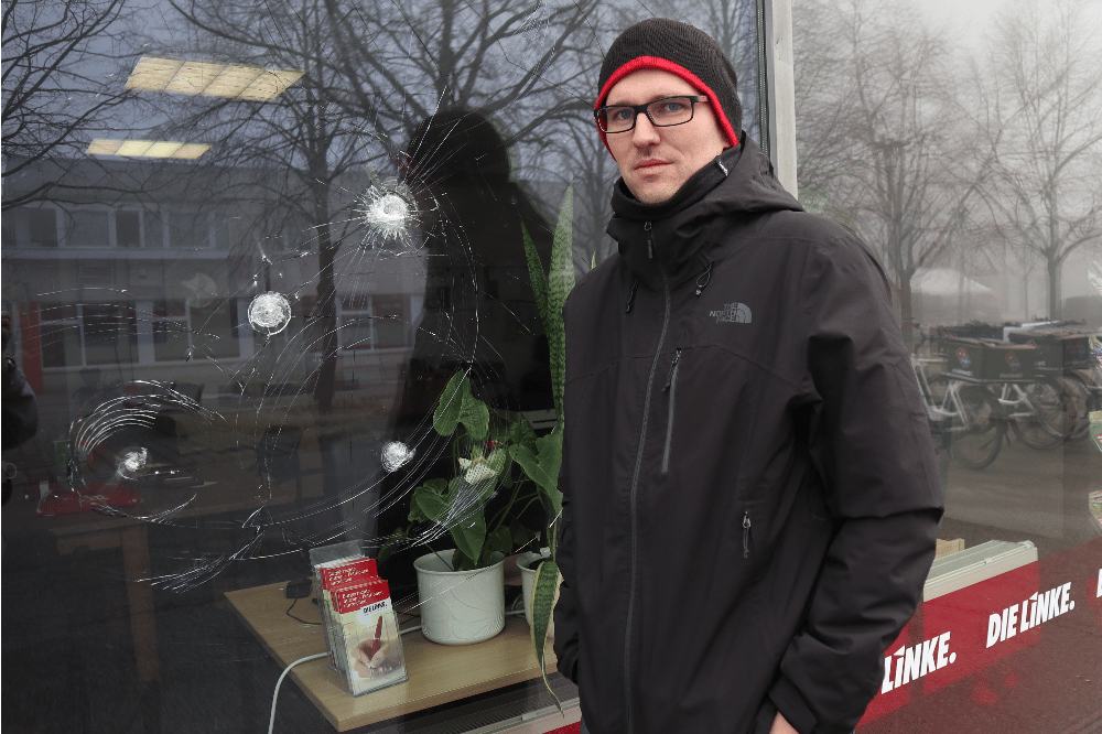 Dr. Adam Bednarsky vor der attackierten Scheibe im Abgeordnetenbüro der Partei DIE LINKE in Grünau. Quelle: Sören Pellmann, MdB