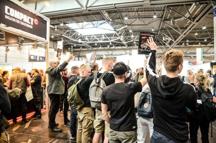 Haben was gegen Gesang - junge Männer versuchen das rechtsradikale "Compact"-Magazin in die Kameras zu halten. Foto: Tim Wagner