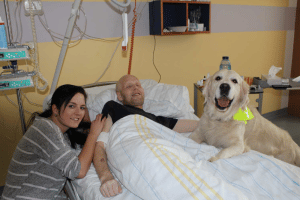 Zusammen mit seiner Halterin Daniela Trambowsky (li.) besucht Therapiehund Sunny schwerkranke Patienten der Palliativstation des UKL auf ihren Zimmern und sorgt für Momente der Freude. Der Patient auf diesem Foto ist in der Zwischenzeit leider bereits verstorben. Foto: privat