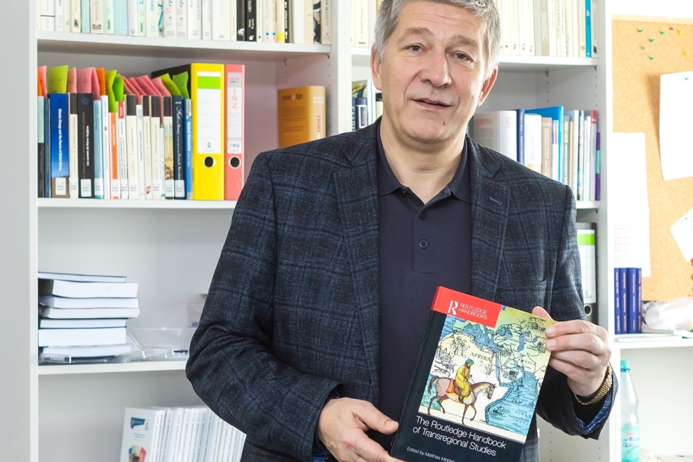 Professor Matthias Middell mit dem von ihm herausgegebenen "Routledge Handbook of Transregional Studies". Foto: Swen Reichhold/Universität Leipzig