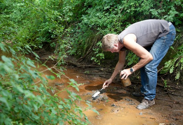 Dietmar Mieth nimmt aus einem Wassergraben in der N&auml;he der Anlage eine Sedimentprobe. Foto: Michael Billig