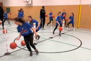 Dribbeln ist eine der Übungen bei der kinder+Sport Basketball Academy. Adika Peter-McNeilly hat es den Kindern zuvor erklärt. Foto: Kant-Gymnasium