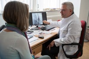Dr. Norbert Klein, Leiter der Abteilung für Rhythmologie und invasive Kardiologie am Klinikum St. Georg, im Gespräch mit seiner ersten Patientin, die er mit der Noble-Stitch-Methode operiert hat. Foto: KSG
