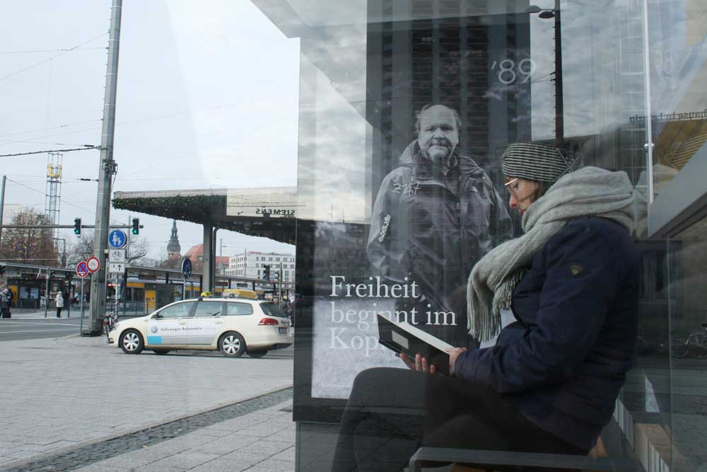 Leserin im Wartehäuschen mit Uwe-Schwabe-Motiv: Freiheit beginnt im Kopf. Foto: Ralf Julke