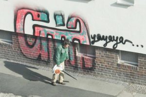 Connewitzer Graffiti und emsige Laubbläserin. Foto: Ralf Julke