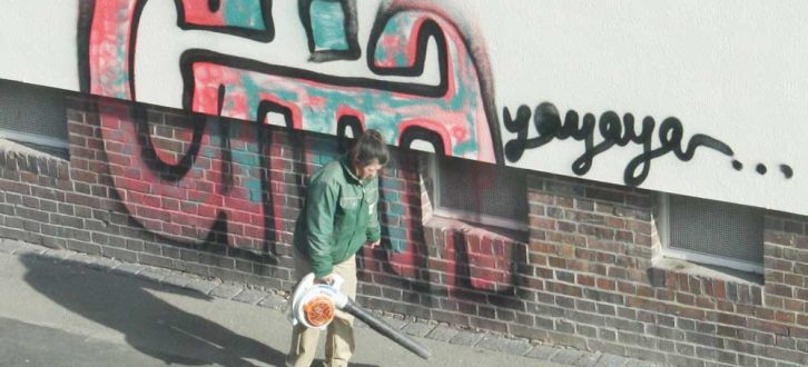 Connewitzer Graffiti und emsige Laubbläserin. Foto: Ralf Julke