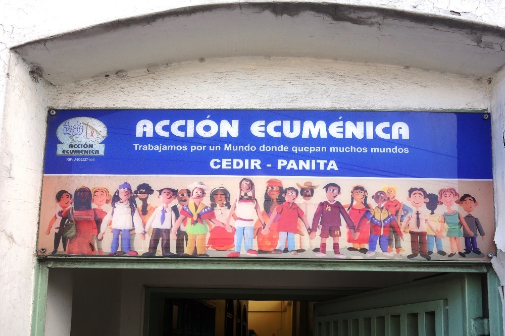 Eingang zum Gesundheitszentrum in einem Armenviertel in Caracas (Venezuela). Über der Tür steht der Leitspruch: „Wir arbeiten für eine Welt, in die viele Welten passen“. © Gustav-Adolf-Werk