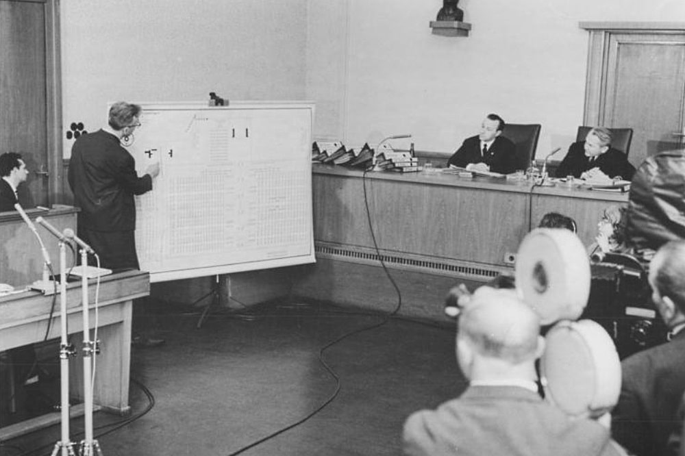 März 1966: Der vor dem Obersten DDR-Gericht angeklagte Auschwitzer Lagerarzt Horst Fischer zeigt an einer Tafel die Krematorien des Vernichtungslagers. Fischer wird im Juli 1966 hingerichtet. © Bundesarchiv