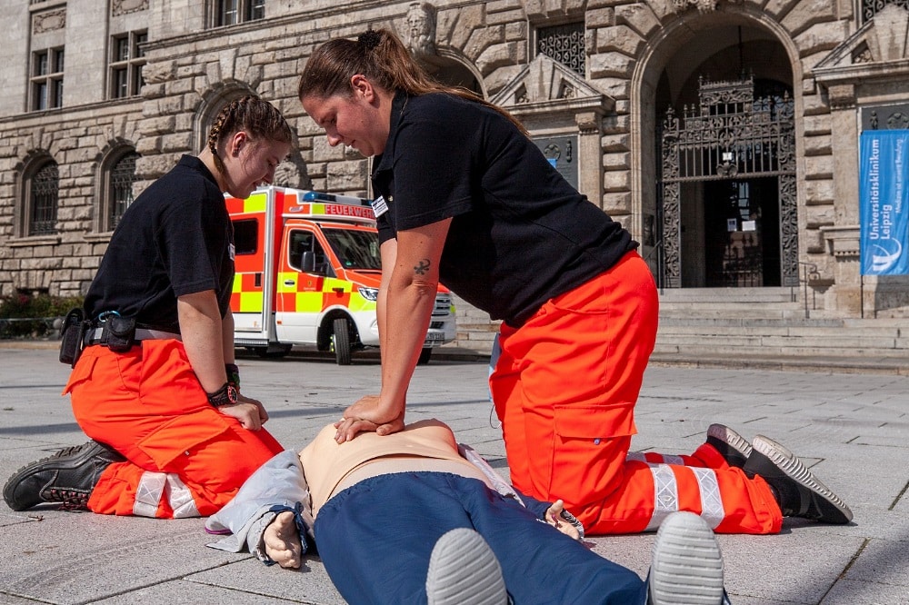Es kommt auf jede Minute an: Sophie Kung (li.) und Doreen Kupfer (re.) vom „Jugendrotkreuz“ des DRK führen vor der Kulisse des Leipziger Neuen Rathauses Wiederbelebungsmaßnahmen an einer Übungspuppe, einem so genannten Dummy, durch. Foto: Hagen Deichsel / UKL
