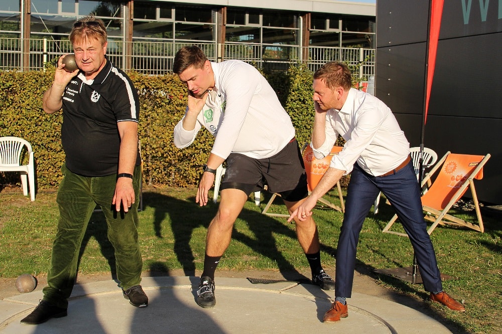 Lernen vom Kugelstoßweltmeister: SC DHfK-Athlet David Storl (Mitte) erklärt Sachsens Ministerpräsident Michael Kretschmer (r.) und SC DHfK-Vereinspräsident Bernd Merbitz die richtige Technik. Quelle: SC DHfK