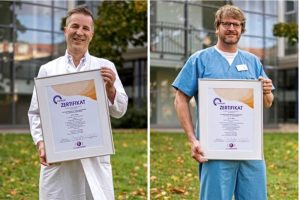 Oberarzt Dr. Ren&eacute; B&ouml;ttcher (links) von der Klinik f&uuml;r An&auml;sthesiologie, Intensiv- und Schmerztherapie sowie der Leitende Oberarzt der Interdisziplin&auml;ren Notaufnahme, Dr. Robert St&ouml;hr, pr&auml;sentieren das neu erlangte Zertifikat &bdquo;Certkom &ndash; Qualifizierte Schmerztherapie&ldquo;. Foto: Kay Zimmermann