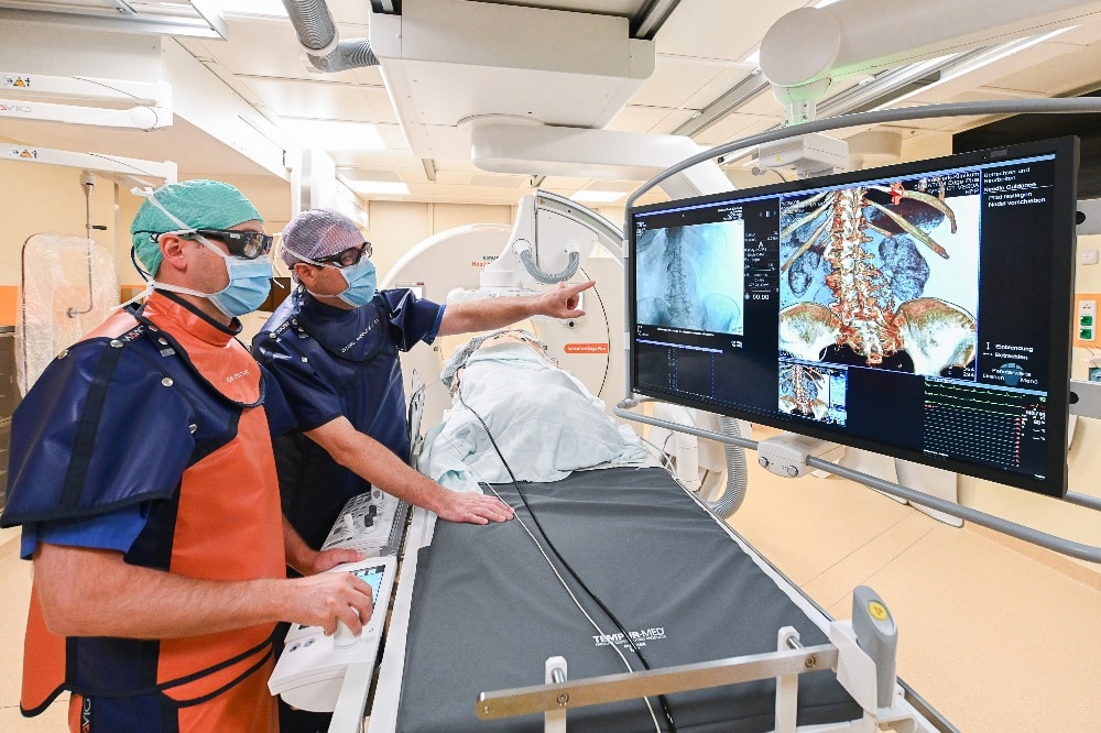 Priv.-Doz. Dr. Michael Moche (blau) und Leitender Oberarzt Jochen Fuchs (orange) im deutschlandweit einzigartigen Interventionsraum. Foto: Thomas Meinicke