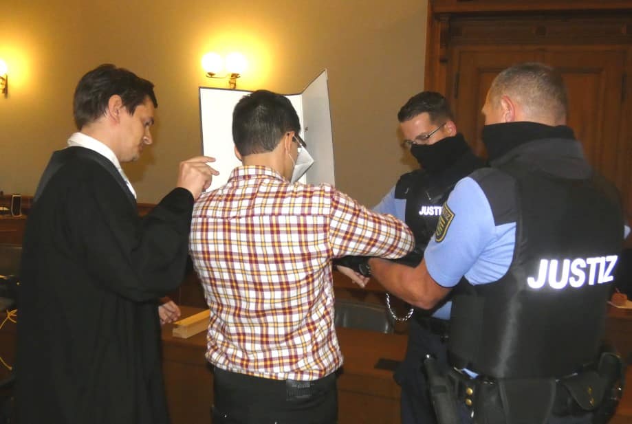 Edris Z. (31, M.) werden zum Prozessbeginn die Handfesseln abgenommen. Links sein Wahlverteidiger Georg K. Rebentrost. Foto: Lucas Böhme