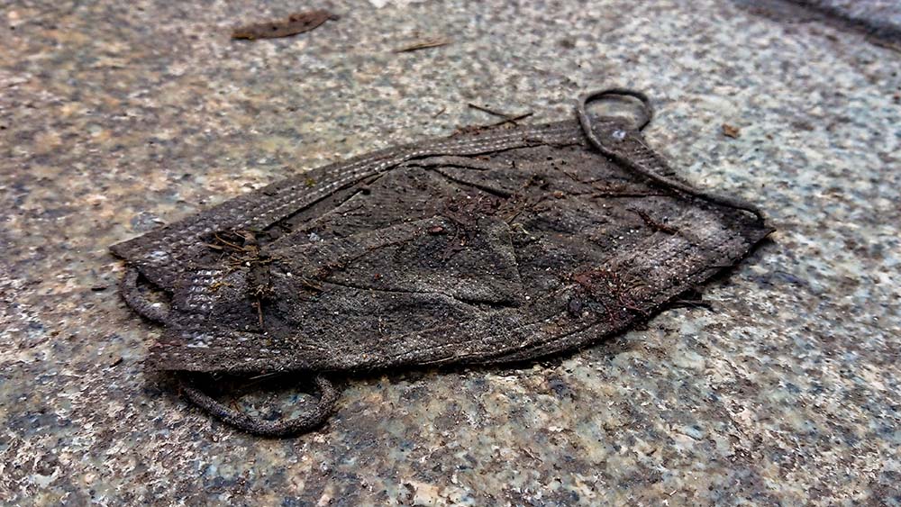 Abfall: Eine weggeworfene schwarze Corona-Schutzmaske liegt auf dem Gehweg